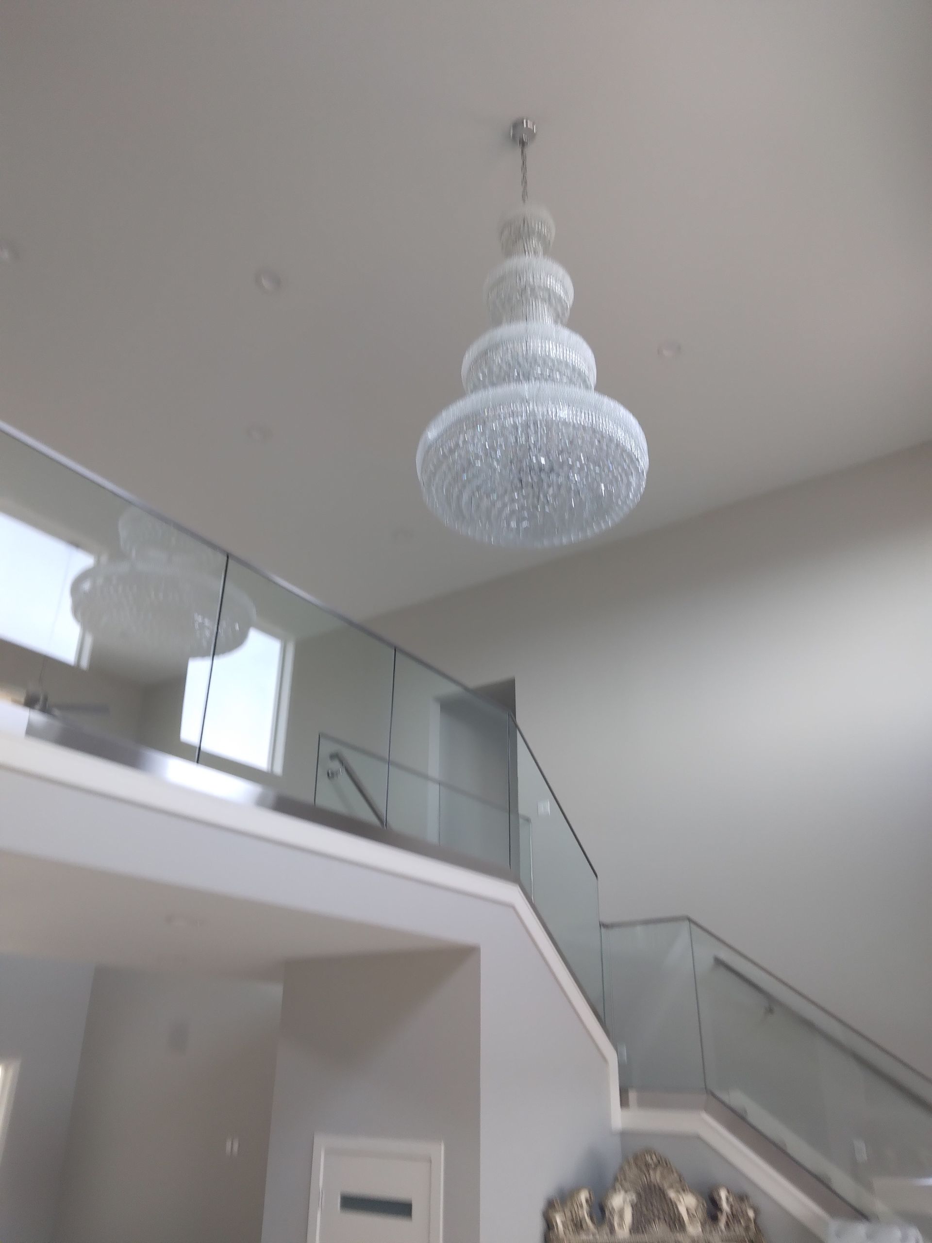 A large chandelier is hanging from the ceiling above a staircase.