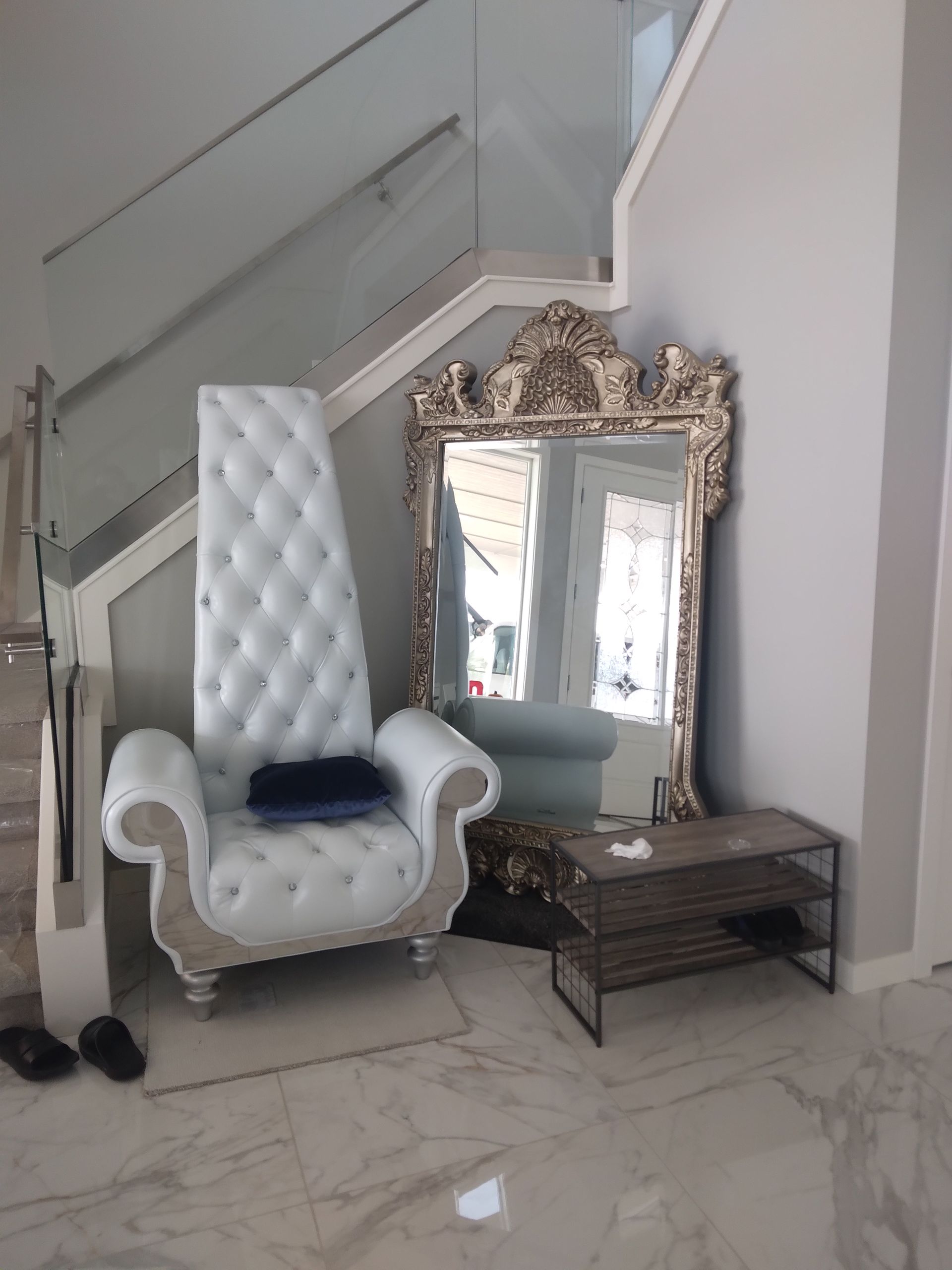A white chair is sitting next to a large mirror in a room.