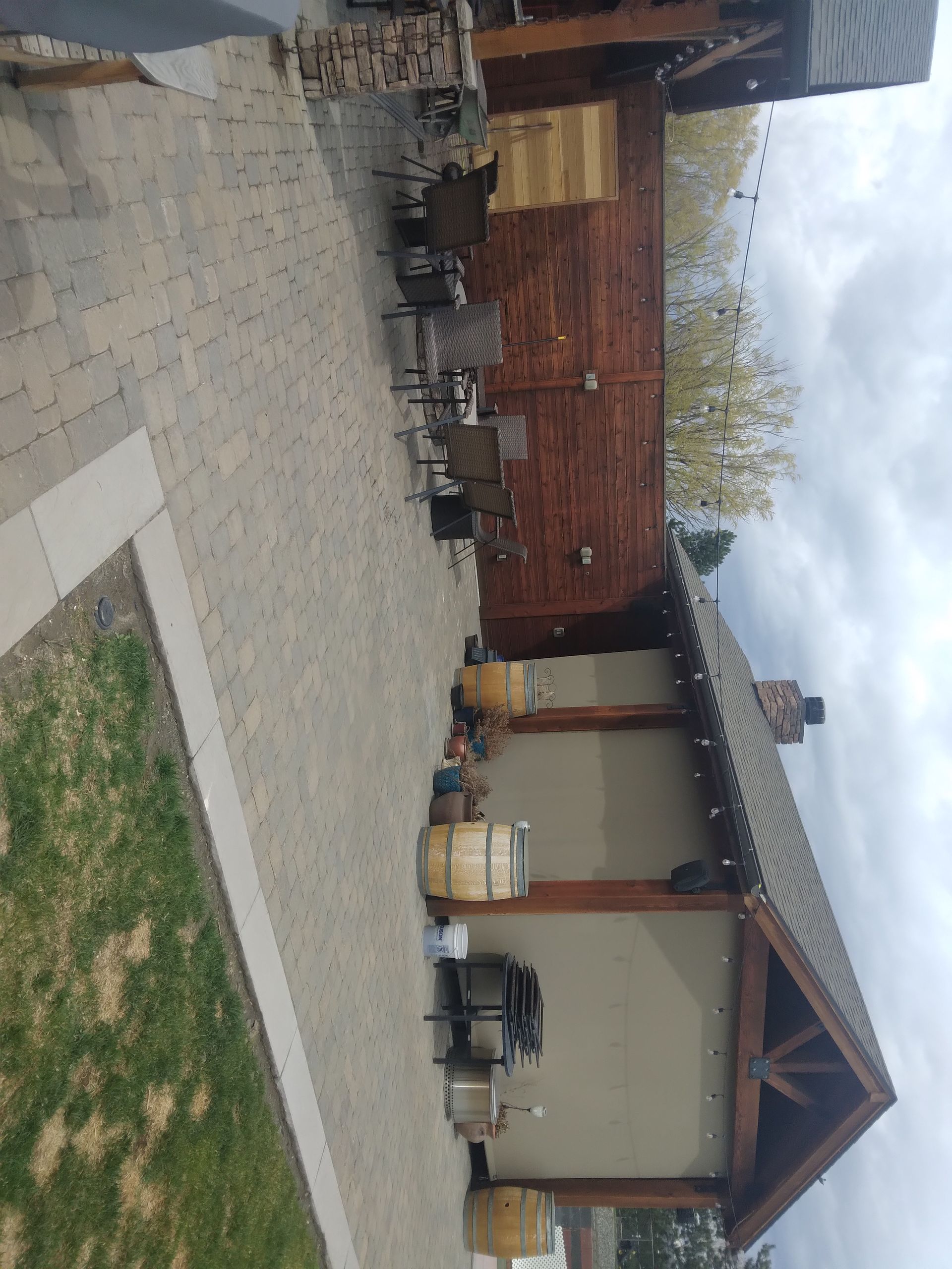 A patio with a brick building and barrels and chairs