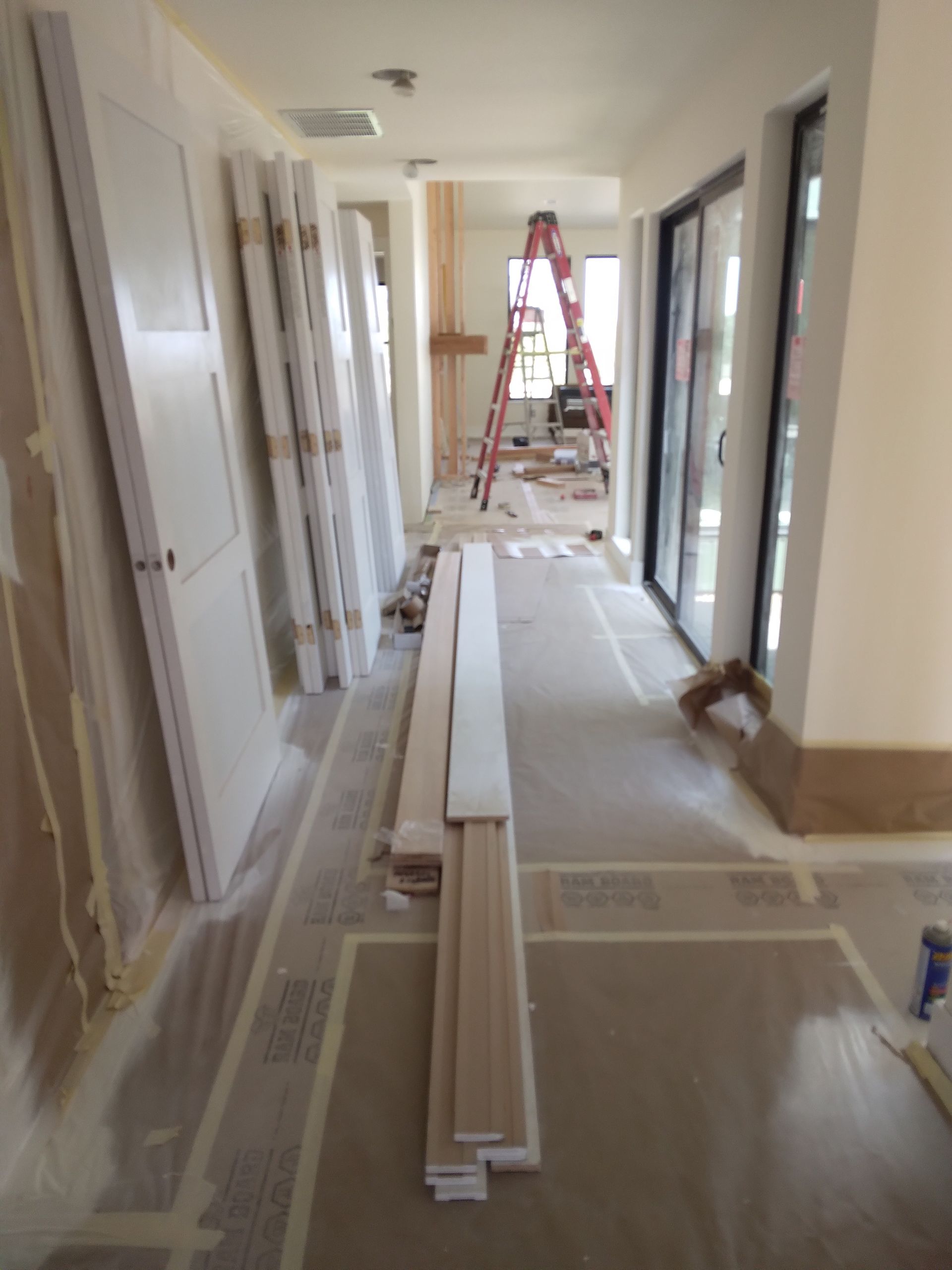A hallway in a house under construction with a ladder in the background.