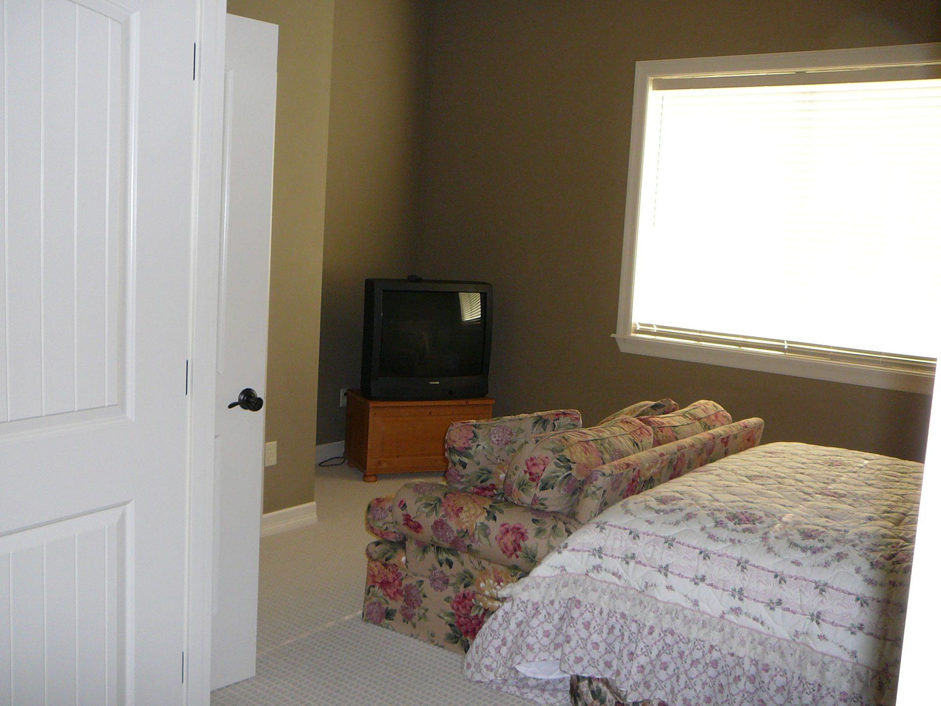 A bedroom with a bed a chair and a television