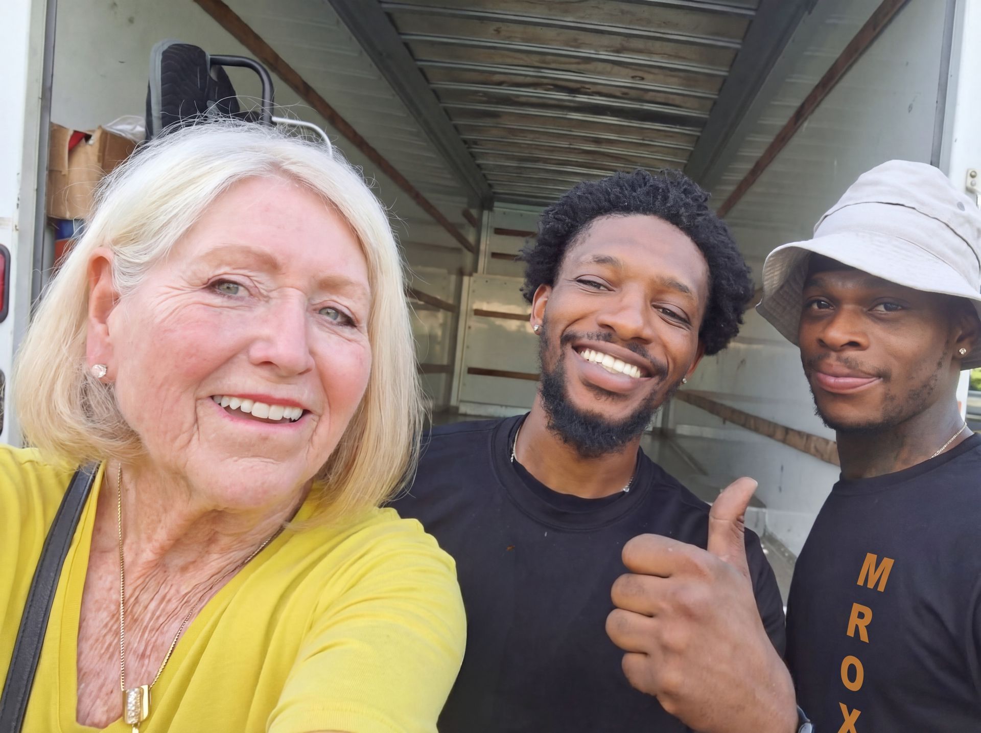 Three smiling people taking a selfie outdoors under a covered walkway