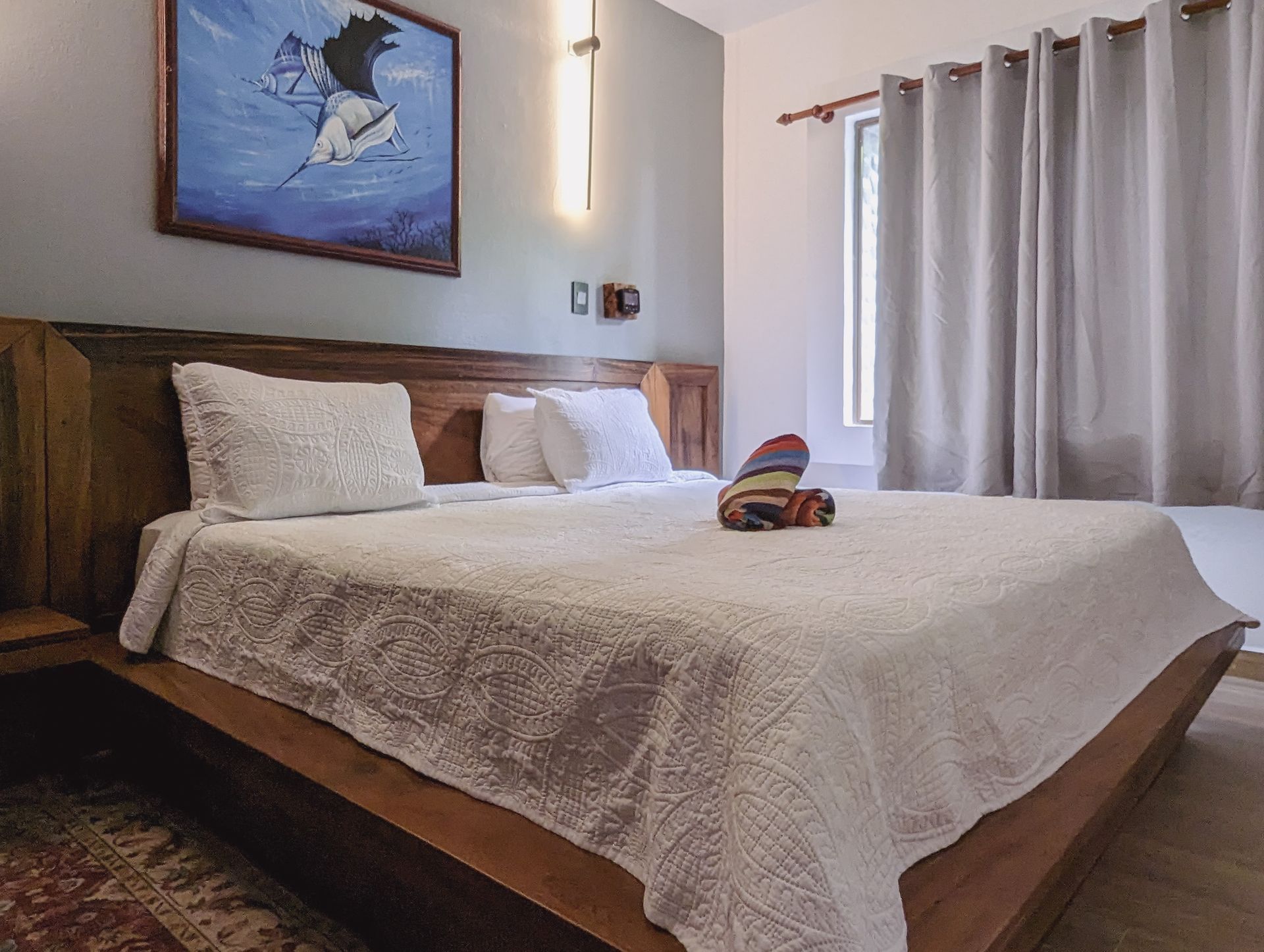 A bedroom with a large bed and a painting on the wall above it.