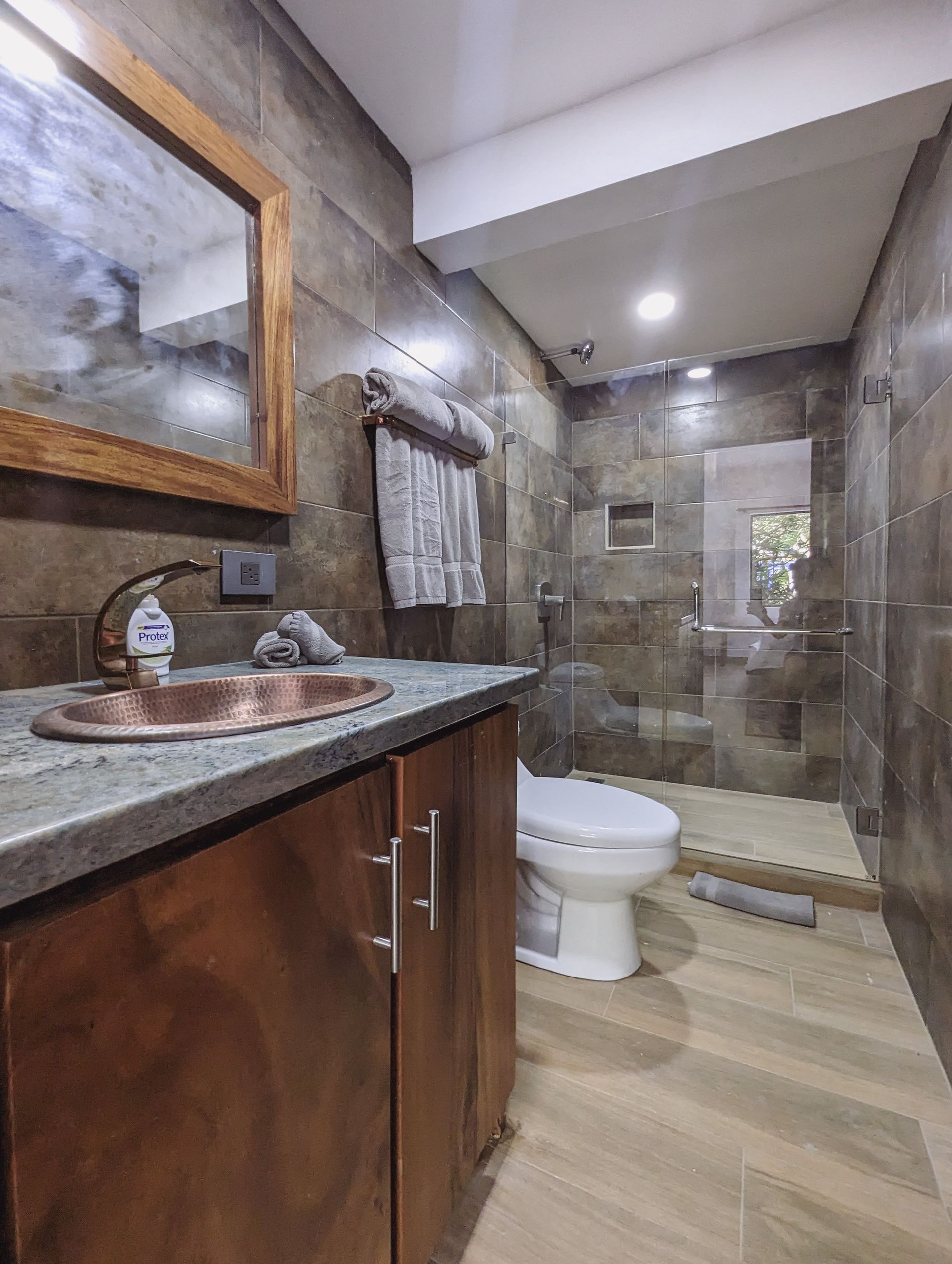 A bathroom with a sink , toilet , mirror and walk in shower.