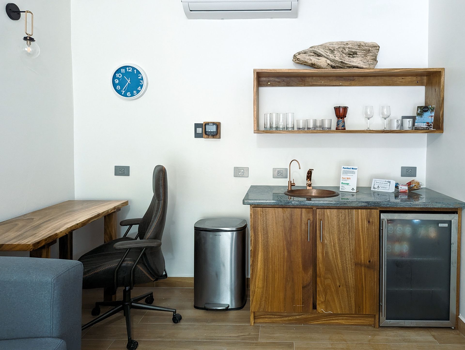 There is a clock on the wall above the sink in the kitchen.
