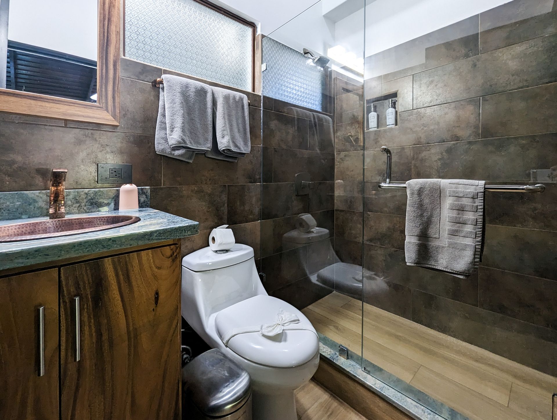 A bathroom with a toilet , sink and walk in shower.