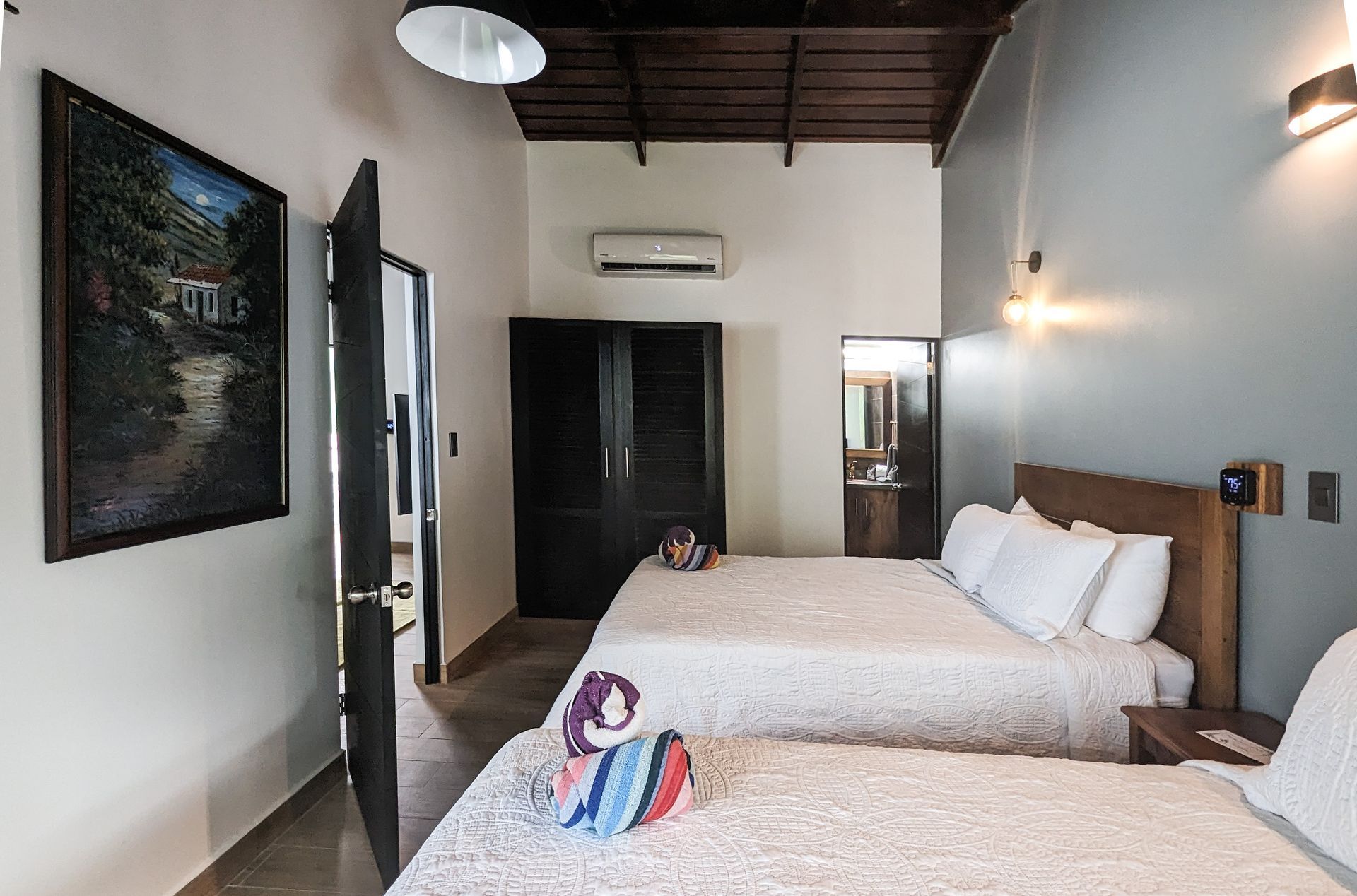 A hotel room with two beds and a painting on the wall.
