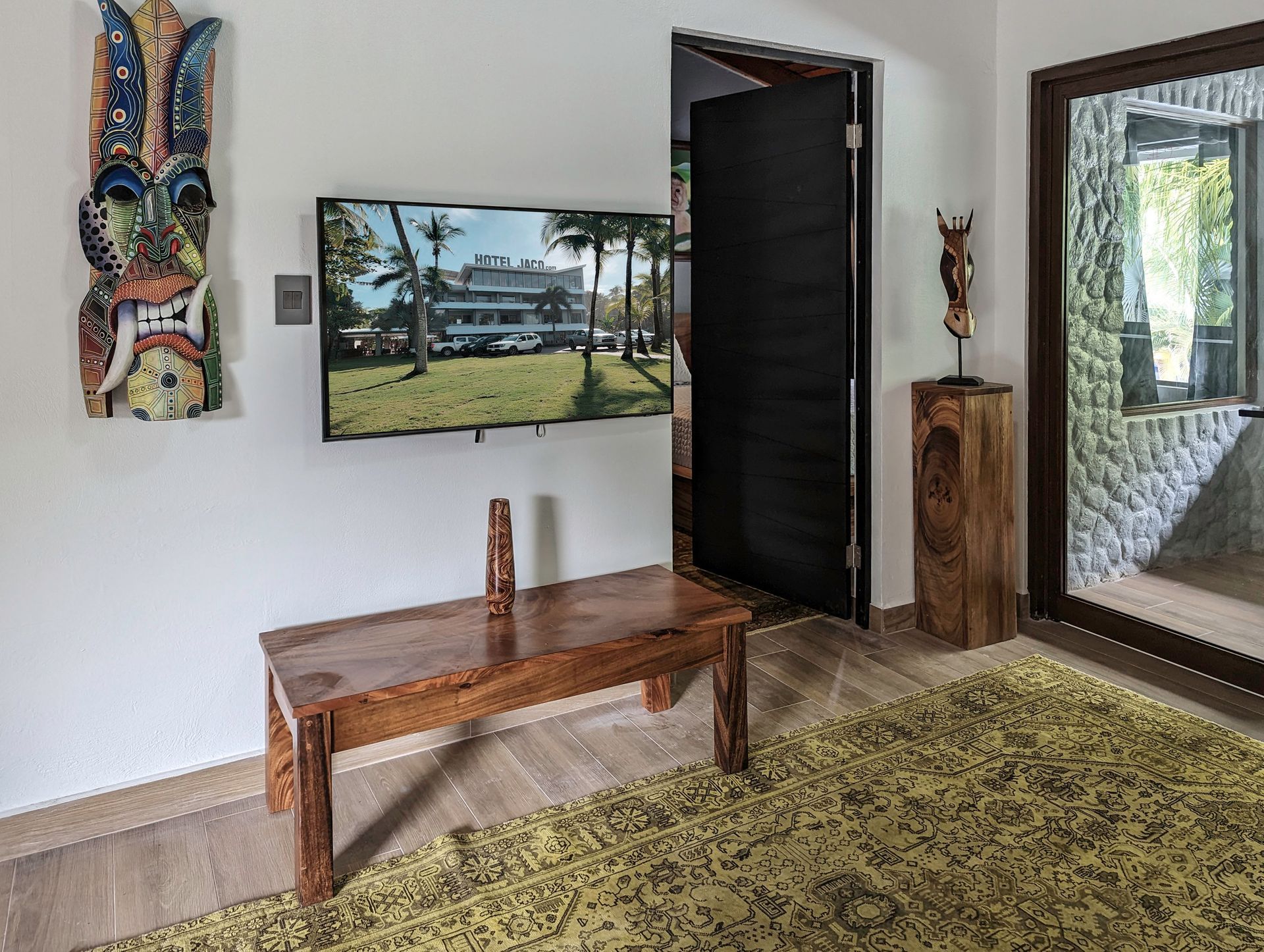 A living room with a wooden table and a flat screen tv on the wall.