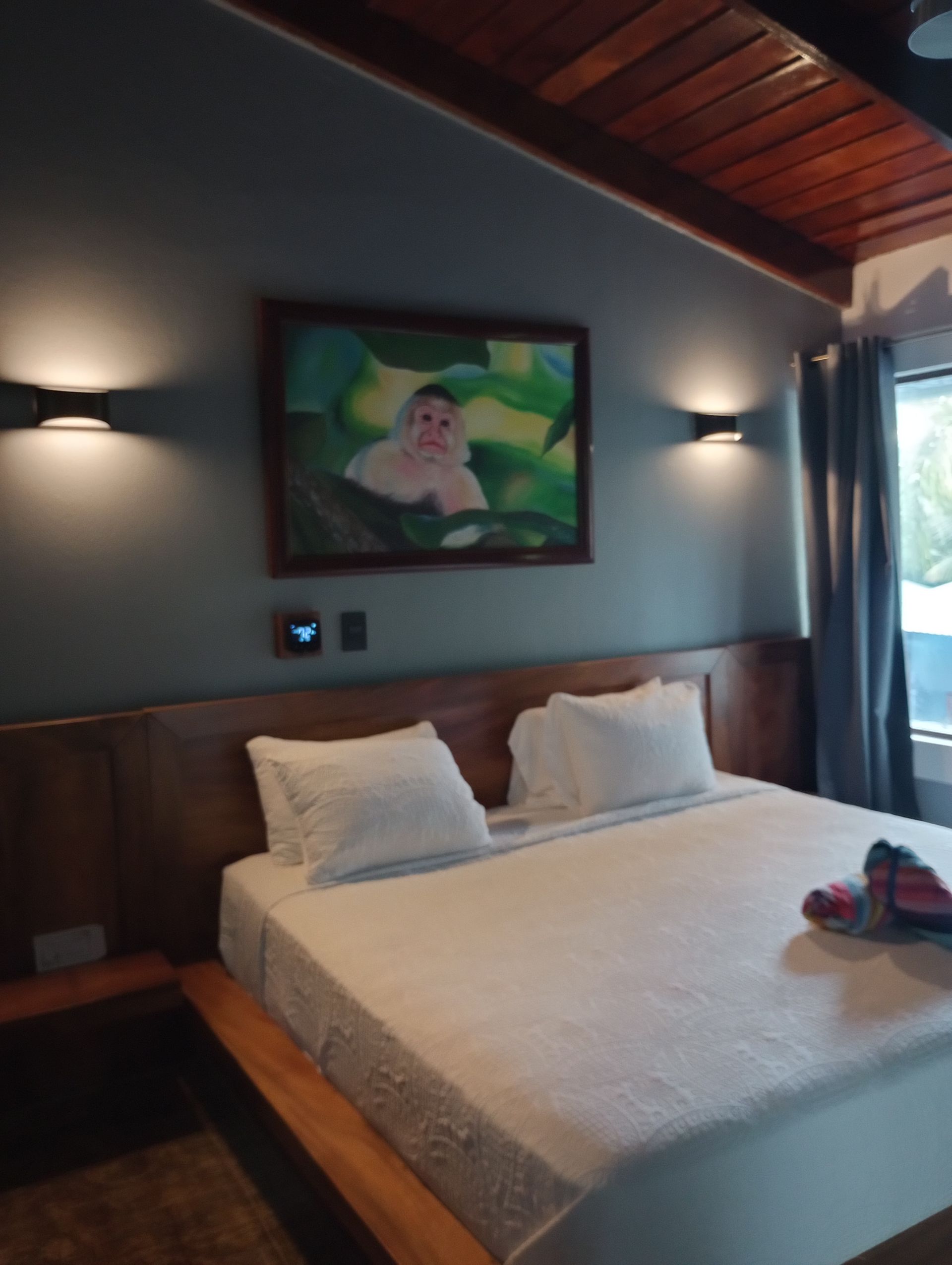 A bedroom with a painting on the wall above the bed