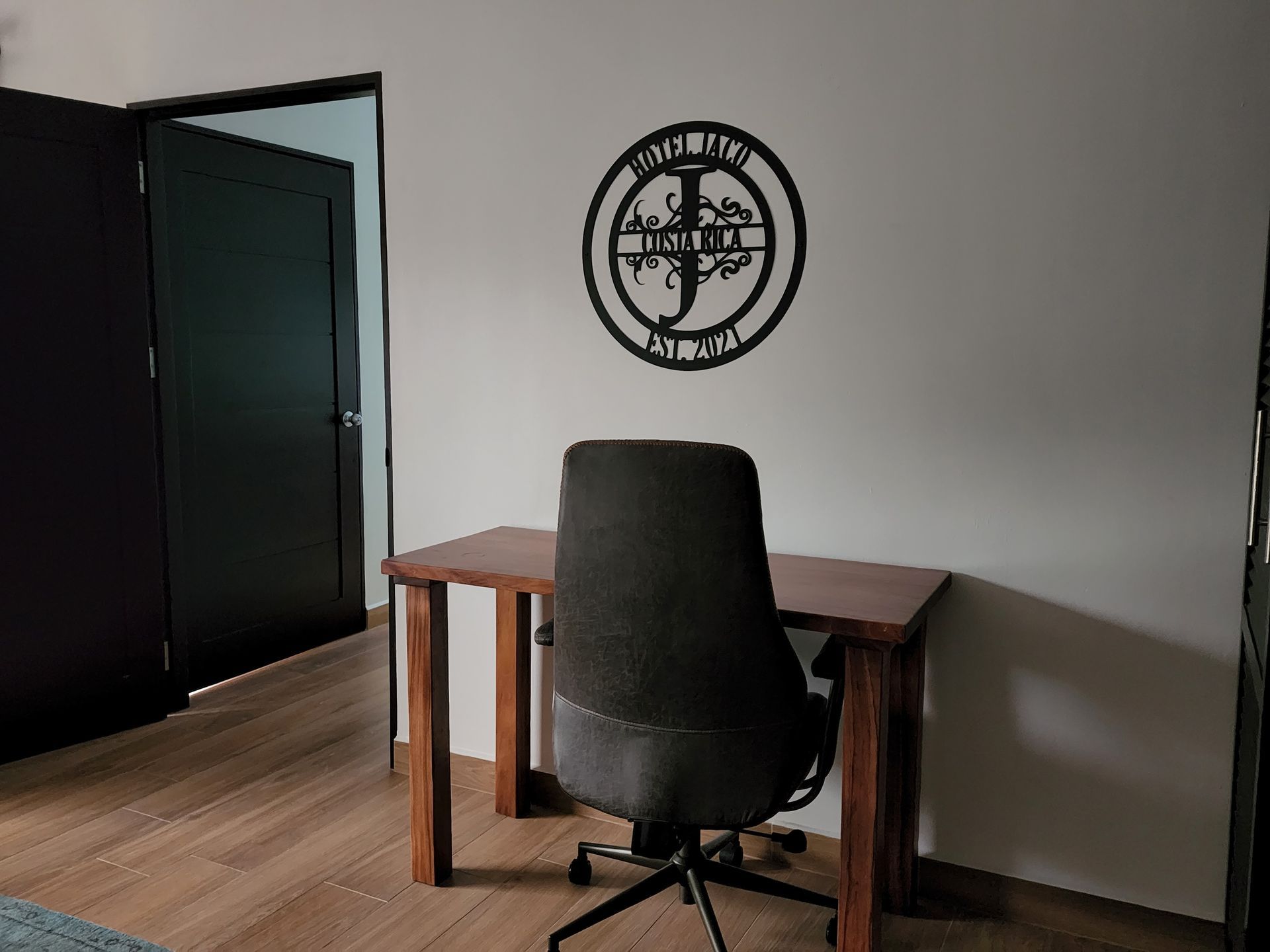 A chair is sitting in front of a wooden desk in a room.