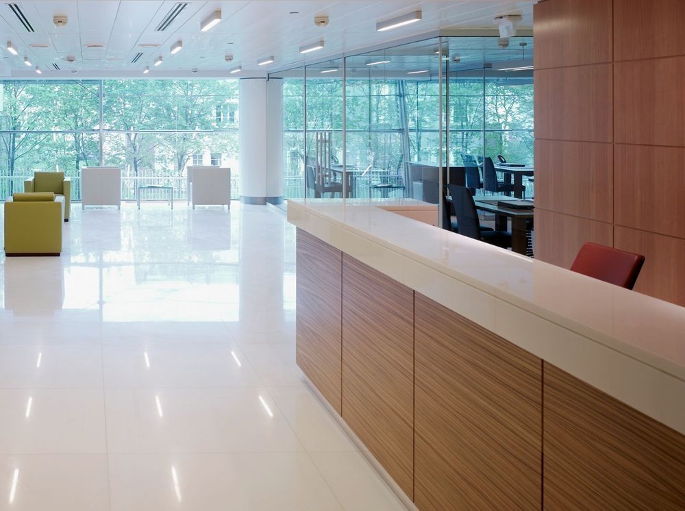 Modern office reception area with wood and white accents, large windows.