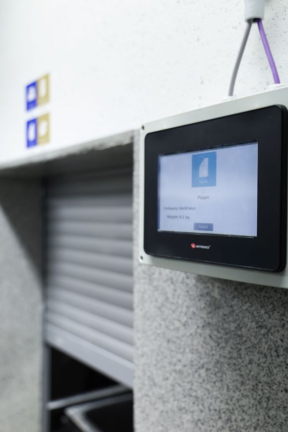 Wall-mounted access screen beside a shuttered doorway in a hallway