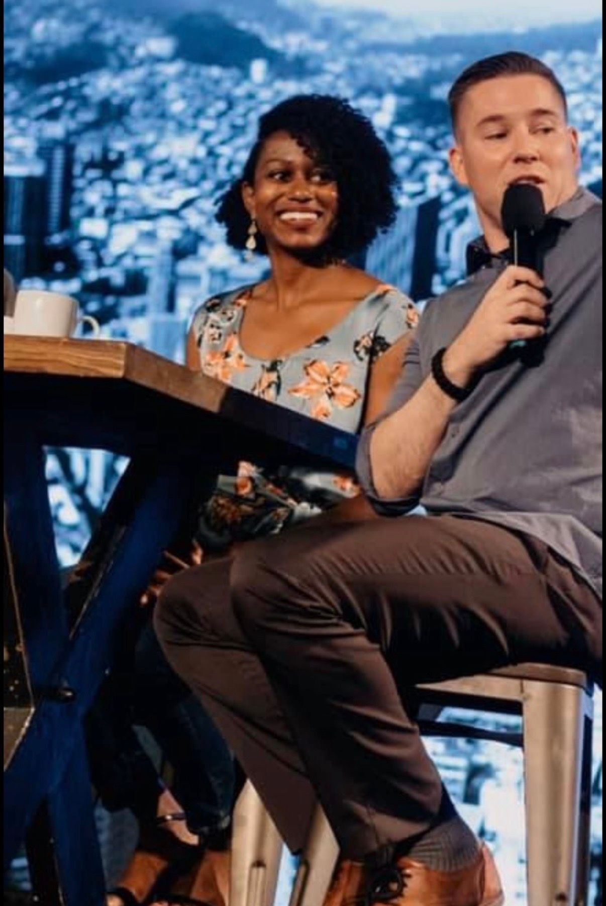 Chad and Sarah-Gayle Galbreath seated together on a panel with a city skyline behind them