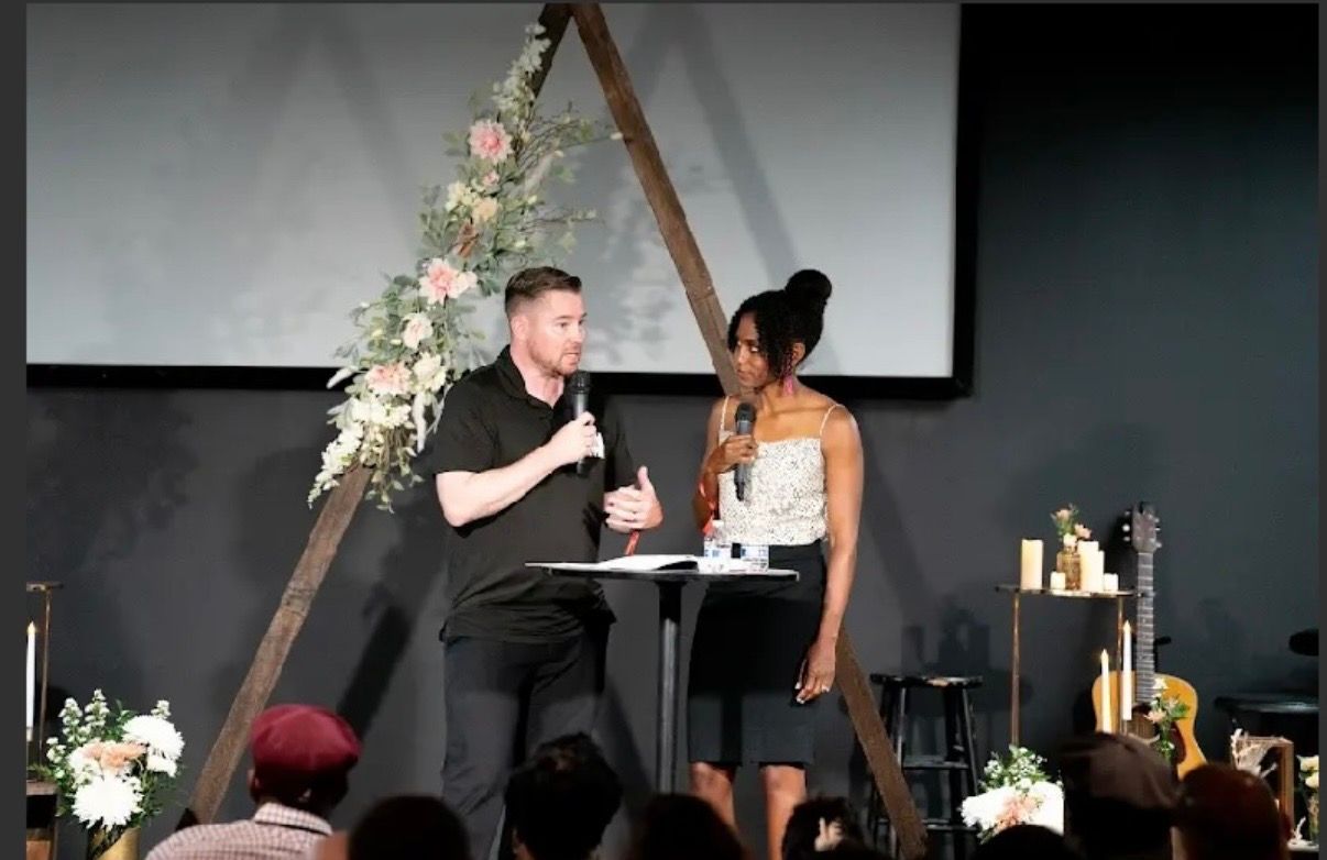 Chad and Sarah-Gayle Galbreath teaching together on stage in front of a floral arch