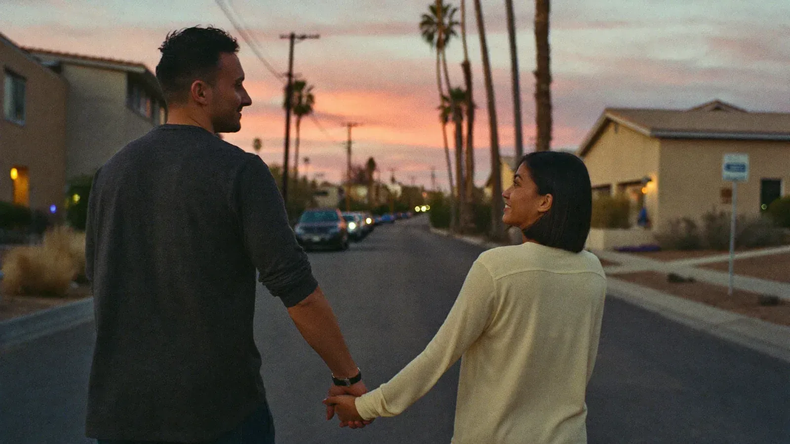 A married couple walking together and holding hands on a quiet neighborhood street at dusk in Gilbert, Arizona