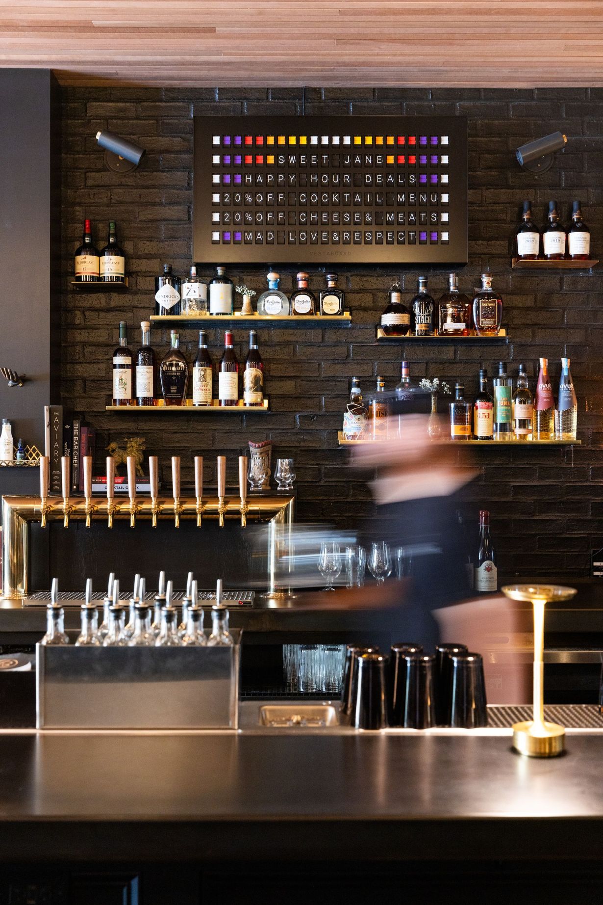 A bar with a lot of bottles on shelves and a bartender behind it