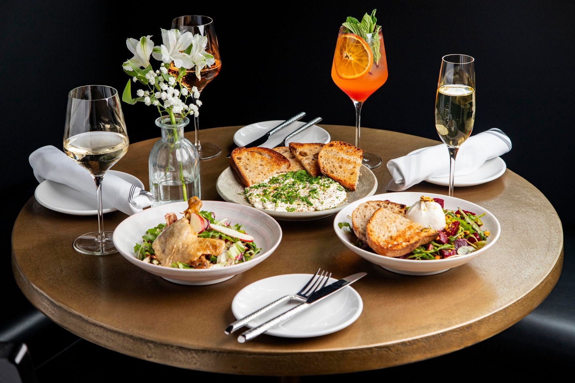 A table topped with plates of food and wine glasses.