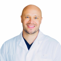 A smiling doctor in a lab coat with a stethoscope around his neck.