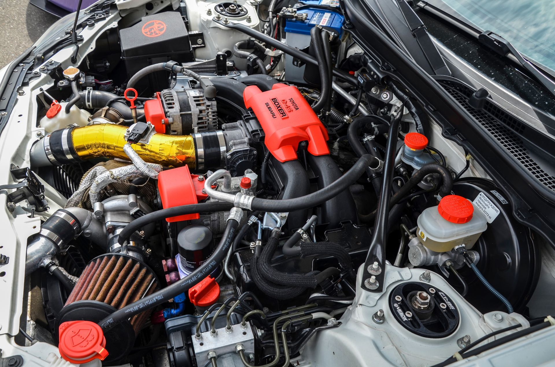 A close up of the engine of a car with the hood open.