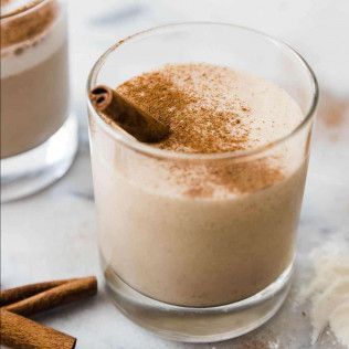 Glass of creamy drink topped with cinnamon and a cinnamon stick.