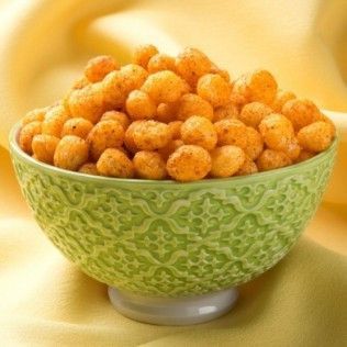 Green bowl filled with orange, puffy peanut snacks.