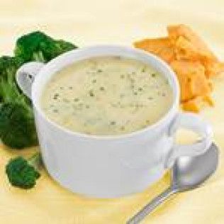 Broccoli cheddar soup in a white mug, with broccoli and cheese on the side.