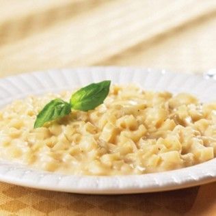 Pasta in creamy sauce, garnished with basil on a white plate.