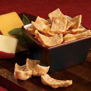 Bowl of crunchy cheese crisps, cheese blocks, on wooden board.