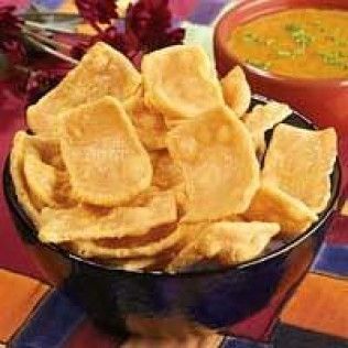 Bowl of fried flatbread chips, with a bowl of sauce in the background.