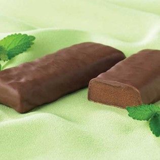 Two chocolate-covered mint patties on a light green cloth, with mint leaves.
