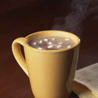 Yellow mug of steaming hot chocolate with marshmallows.