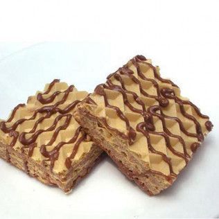 Two square wafer cakes with cream filling, drizzled with chocolate on a white plate.