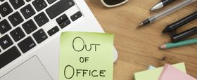 Out of office note beside laptop for HR vacation coverage