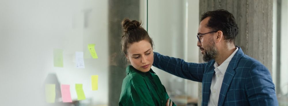 Man making woman uncomfortable in an office representing workplace harassment.
