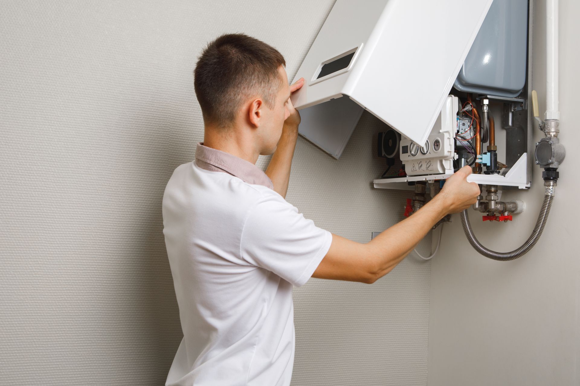 Person inspecting the inside of a wall-mounted boiler with the cover open