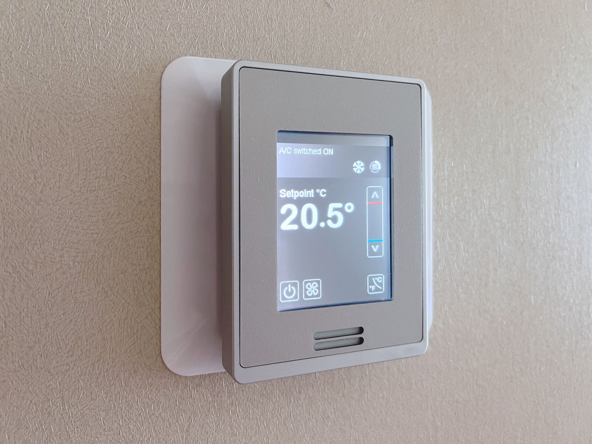 Wall-mounted digital thermostat displaying 20.5°C on a beige wall