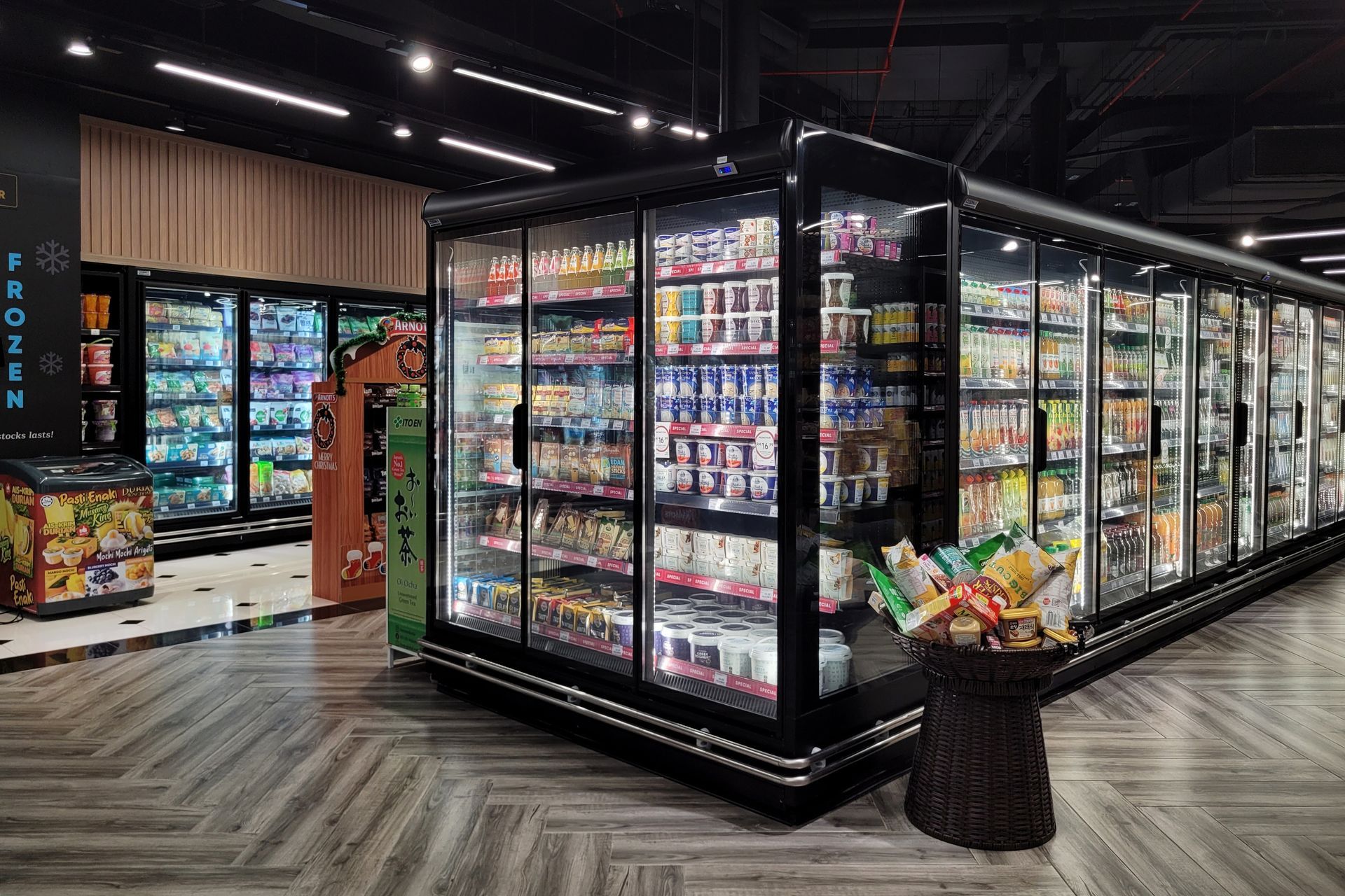 Modern grocery store aisle with glass-door refrigerated display cases and packaged drinks