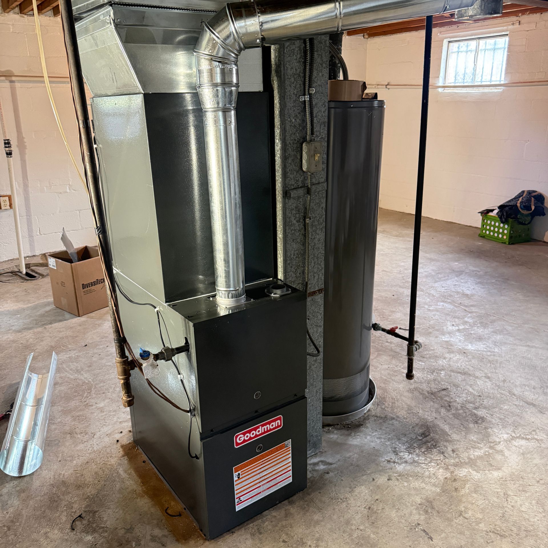 Furnace and ductwork installed in an unfinished basement utility room.