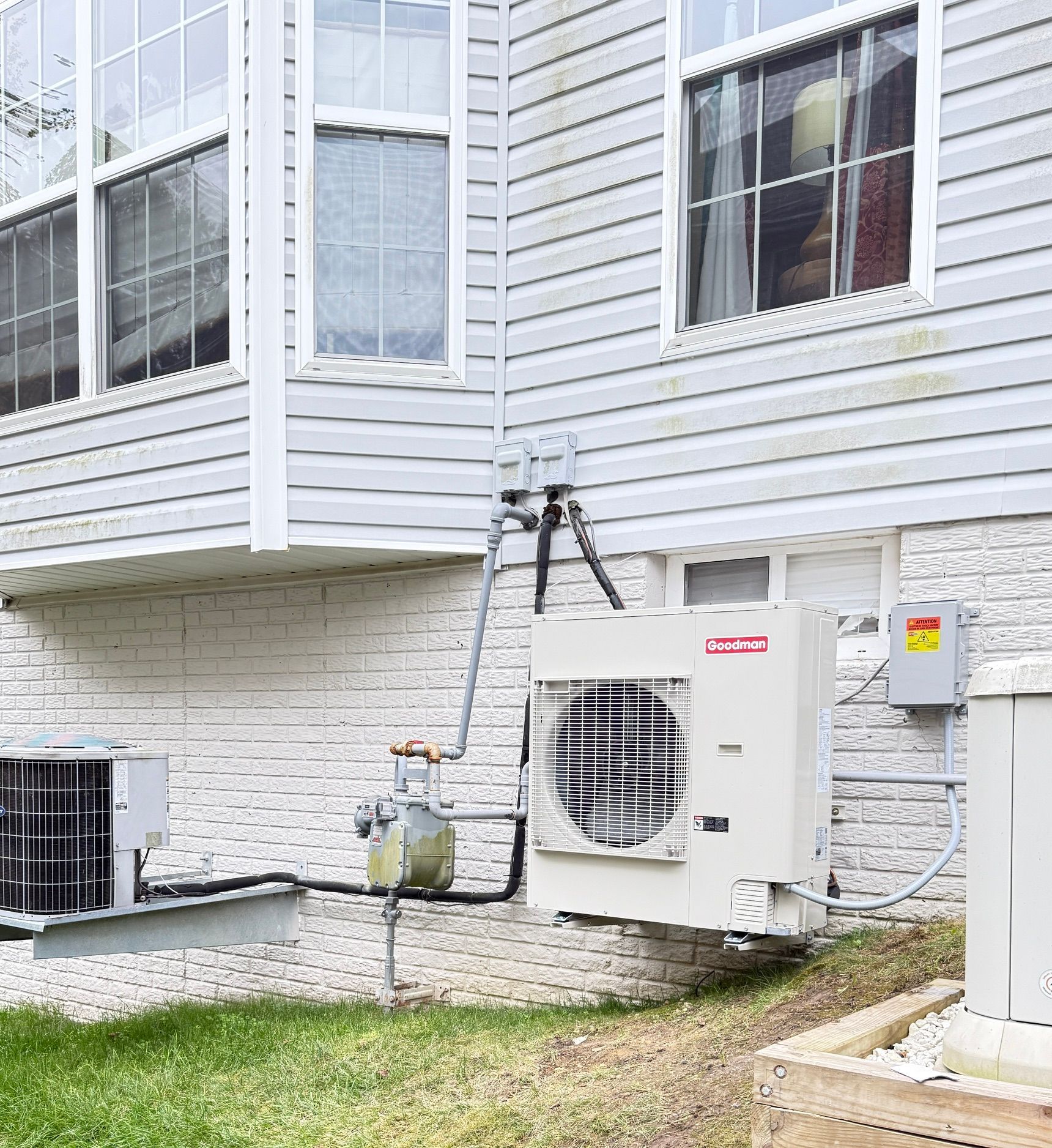 Outdoor air conditioner units beside a building, with grass in the foreground