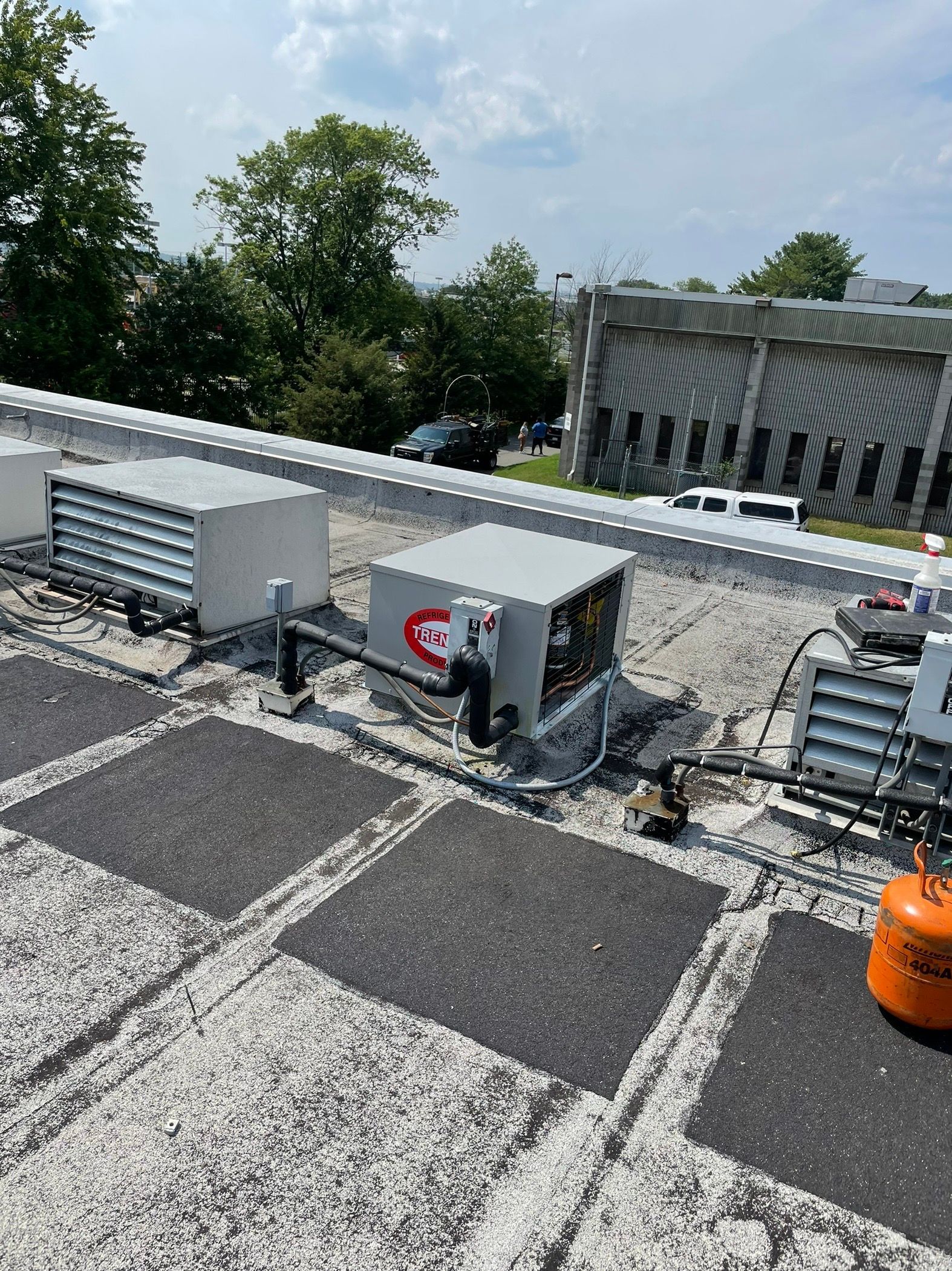 Three outdoor air conditioning units on concrete pads beside a grassy area