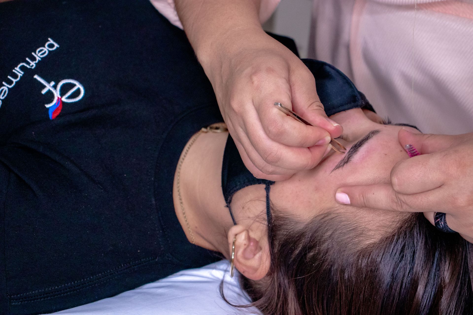 Person having eyebrow makeup applied with a small brush while lying down