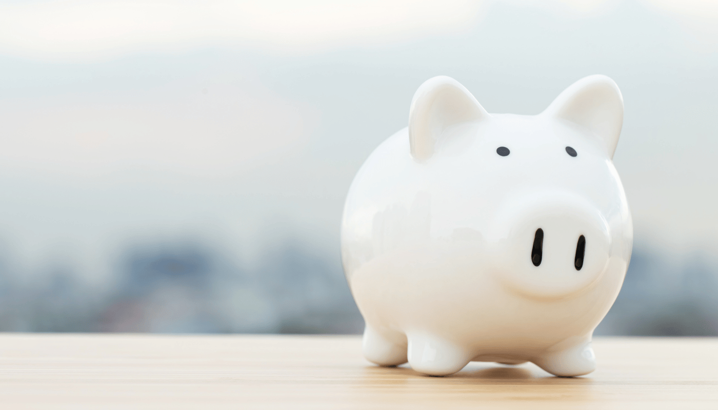 A white piggy bank is sitting on a wooden table.