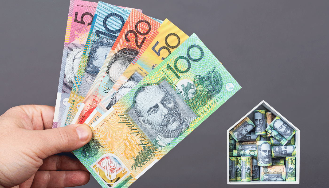 A person is holding a bunch of money in their hand in front of a house.