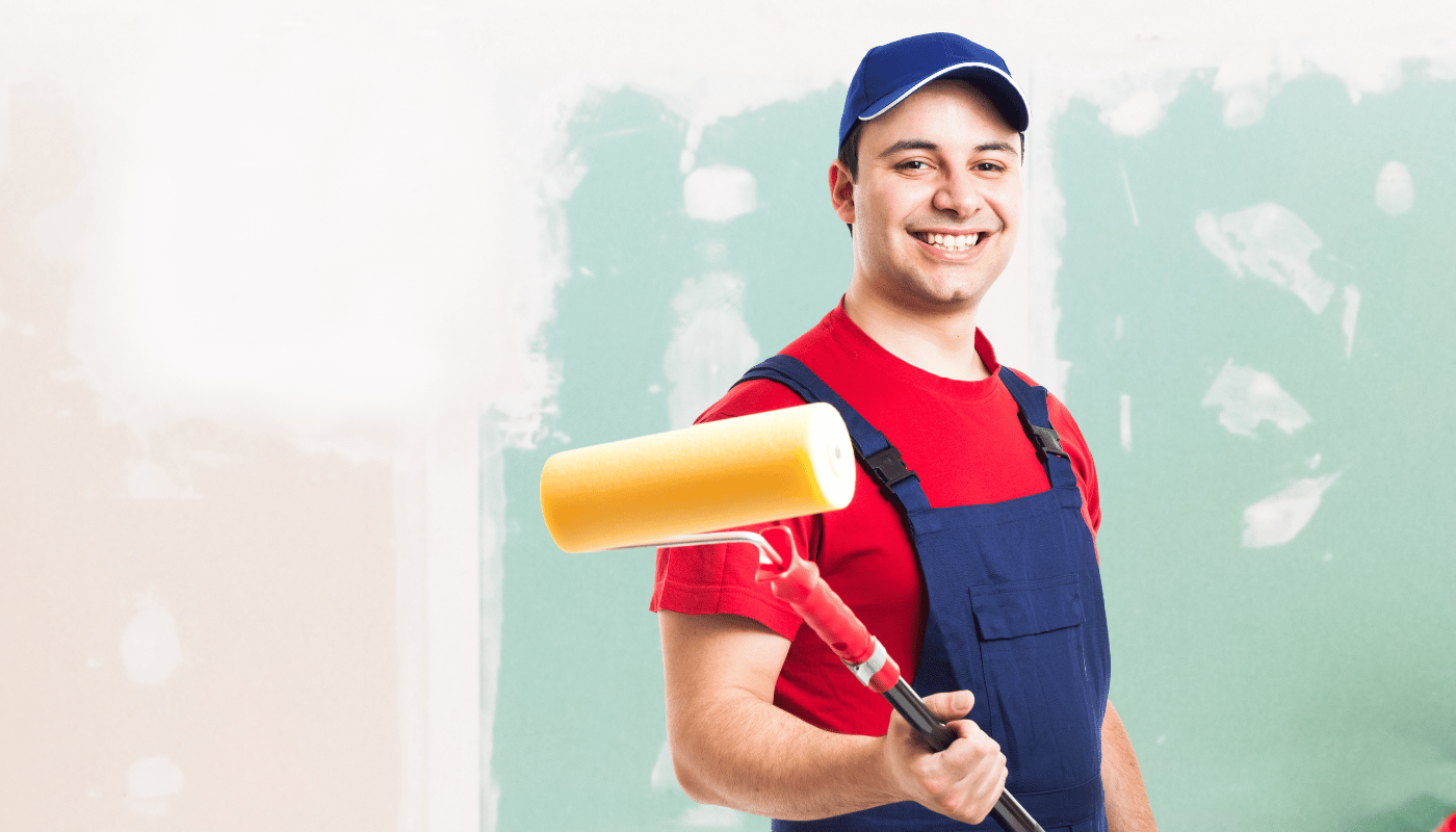 A man is holding a paint roller in front of a wall.
