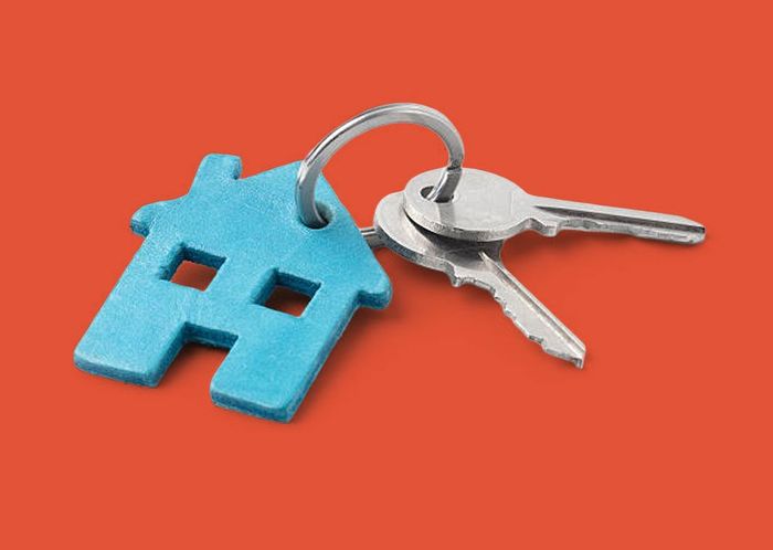Blue house-shaped keychain with two keys on a ring, set against a red background.