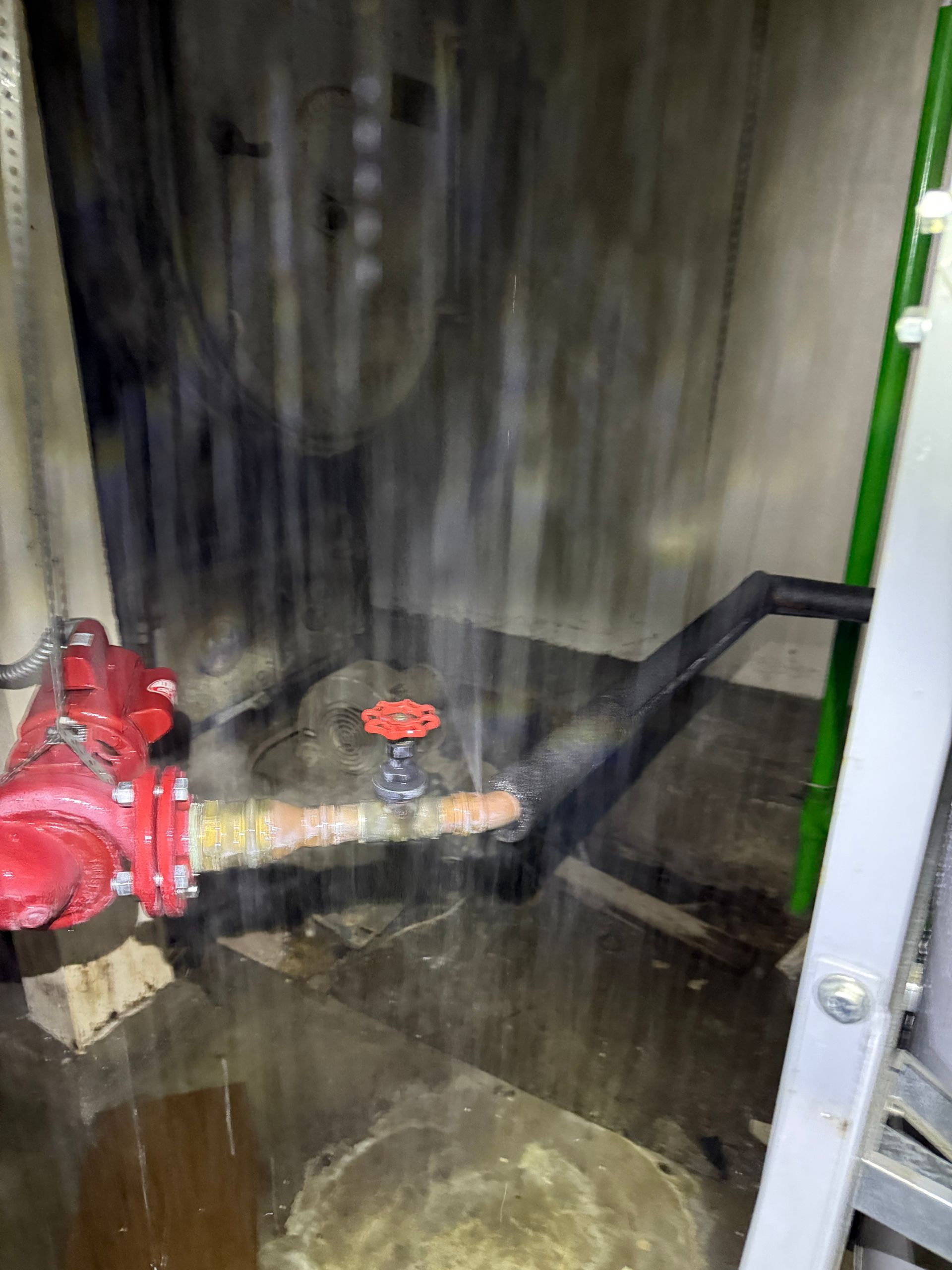 Water gushes from a red fire hydrant in a dimly lit room, flooding the floor. A red valve is visible.