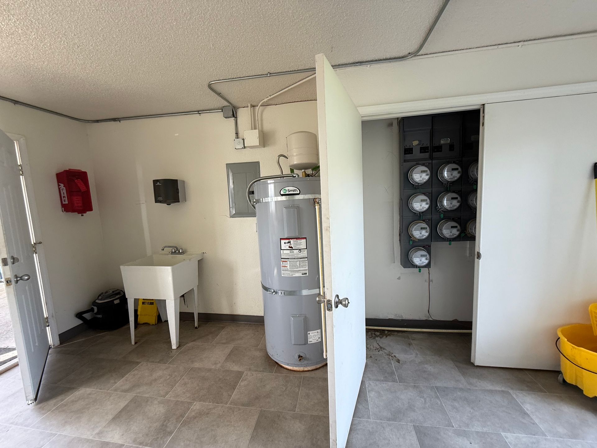 Utility room with water heater, sink, and electrical panel. Open doors on either side.