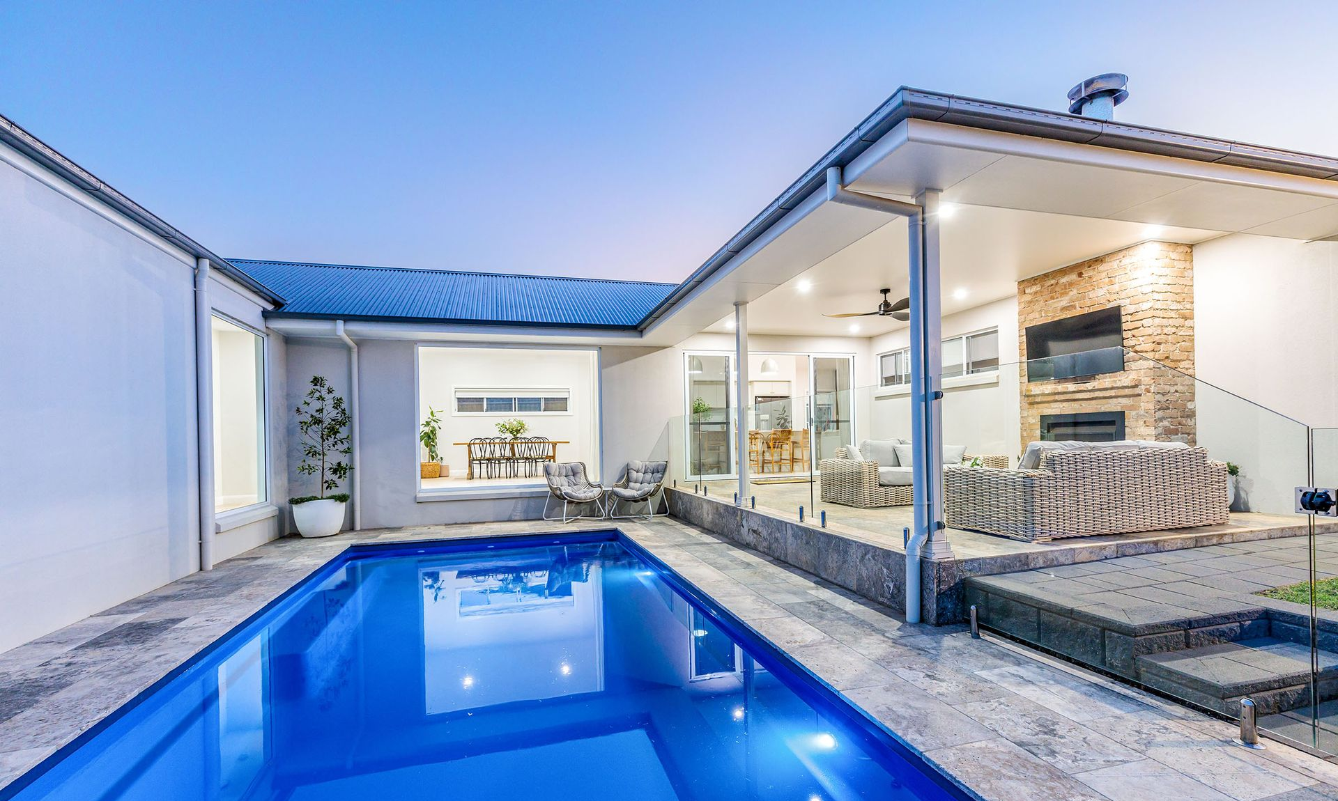 Backyard with pool, patio, and modern home exterior; blue water, neutral tones.