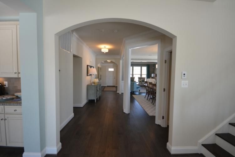 Hallway with dark wood floor, archway, and white walls.