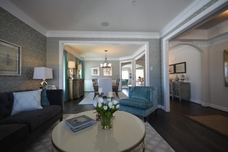 Living room with dark gray sofa, teal chair, and a round coffee table with tulips.